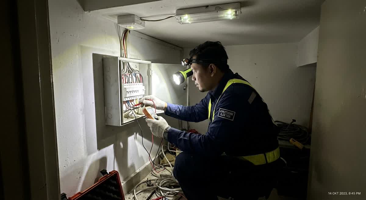 Emergency electrician working on electrical panel in dark room with emergency lighting