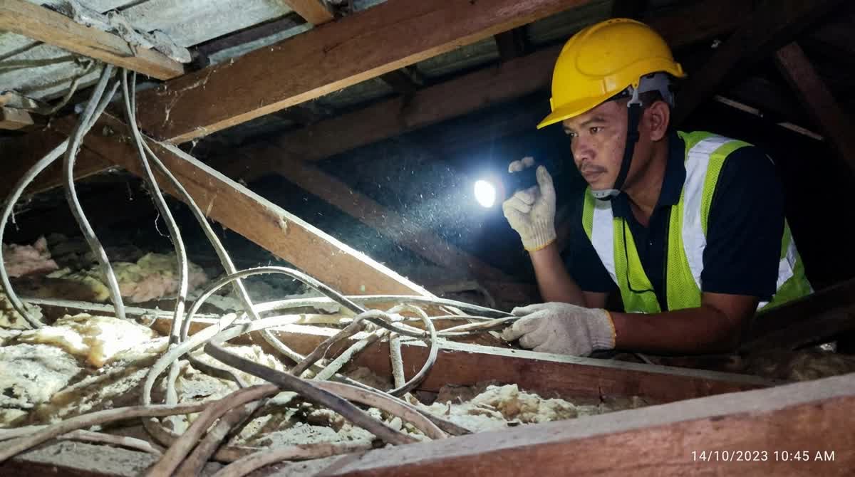 Electrician inspecting old wiring in a Malaysian home during a safety assessment